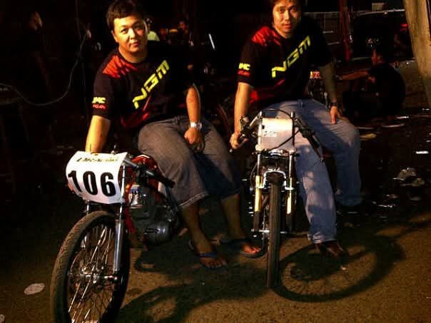 Two NGM team riders posing with their bikes, race bib 106