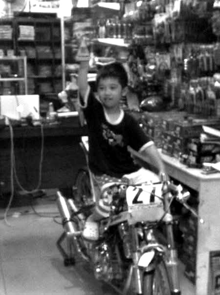 A child sitting on a racing bike inside the shop