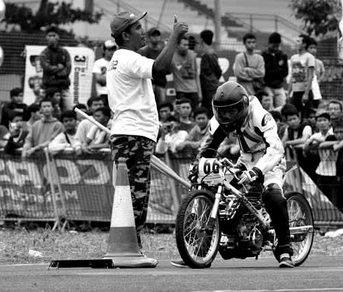 Race official giving the start signal to an NGM rider, race bib 66